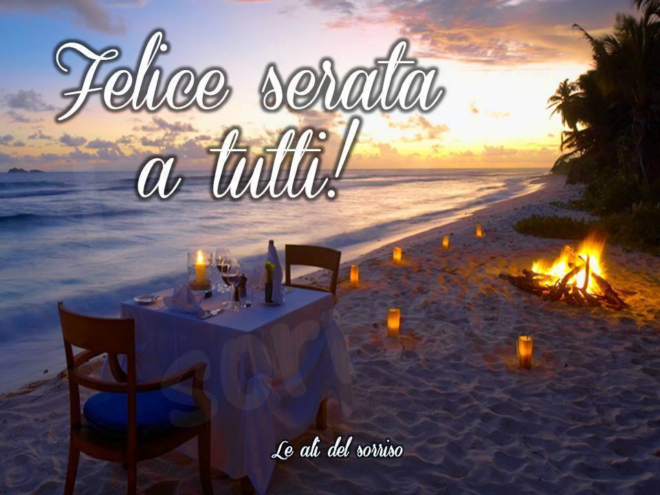 Tavolo elegante su spiaggia al tramonto, con fuoco e candele