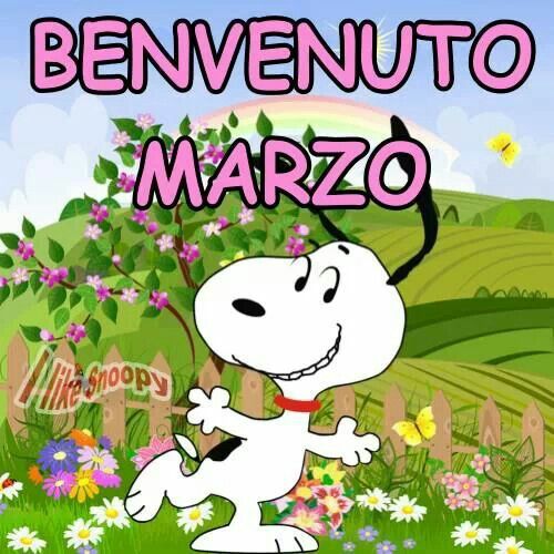 Snoopy salta felice in un prato fiorito con scritta BENVENUTO MARZO
