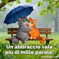 Due gattini si abbracciano su una panchina sotto un ombrello blu mentre piove, con foglie verdi sopra
