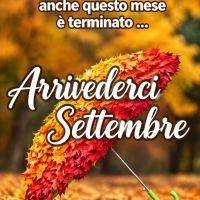 Ombrello ricoperto di foglie autunnali rosse e gialle su un viale, con scritta di saluto a settembre