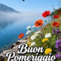 Fiori colorati sulla riva di un lago calmo con montagne in lontananza e cielo azzurro