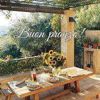 Tavola apparecchiata esterna, testo 'Buon pranzo!' con girasoli