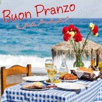 Tavola apparecchiata sul mare con scritta 'Buon Pranzo'