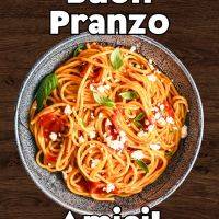 Piatto di spaghetti al pomodoro con basilico e formaggio su sfondo di legno, con scritta di augurio