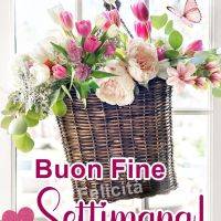 Un cesto di fiori colorati su una finestra con farfalla e scritta di auguri