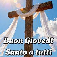 Croce di legno con drappo bianco al sole, cielo azzurro e nuvole, scritta di augurio