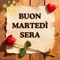 Scritta di auguri su foglio, con rosa rossa, cuore rosso e stelline su tavole di legno